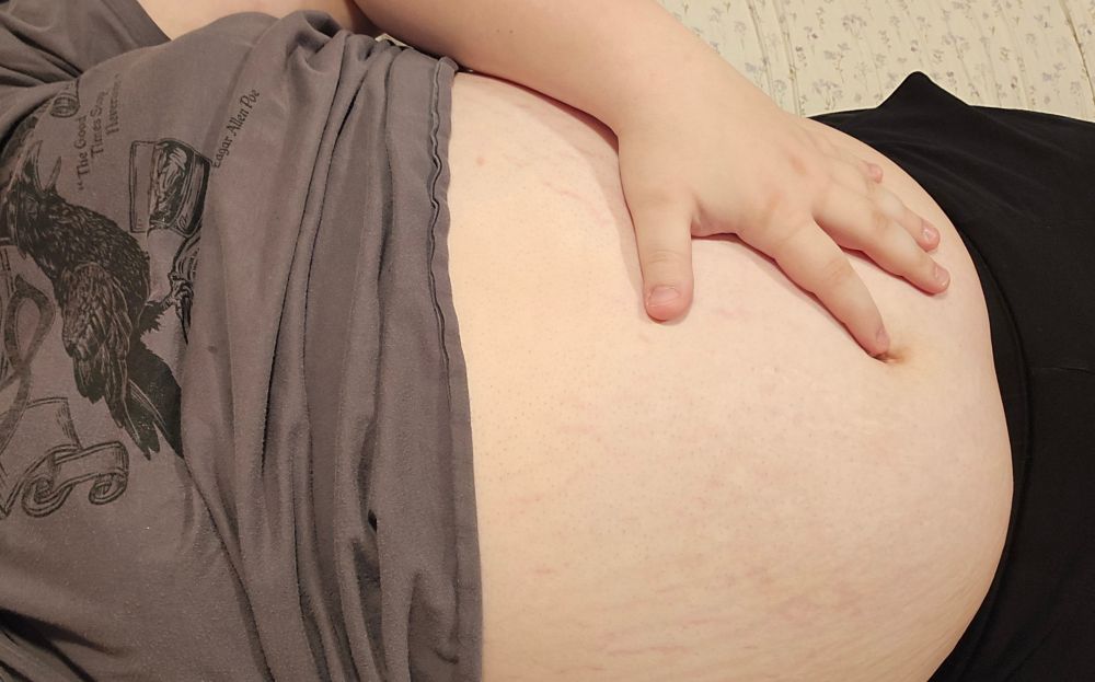 a large girl laying on the bed, with her hand resting on top of her exposed belly