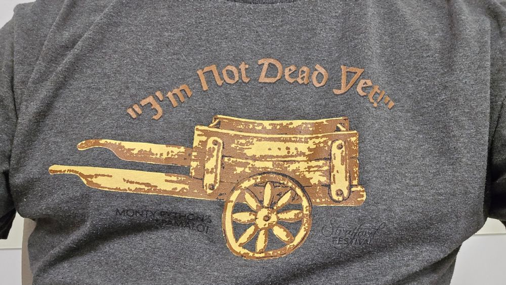 A grey t-shirt with an old, wooden cart reads I'm Not Dead Yet.