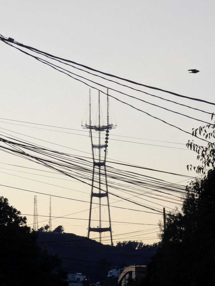 A photo of a three-masted radio tower with several "bobbles" cladding one of the pylons, breaking symmetry.
