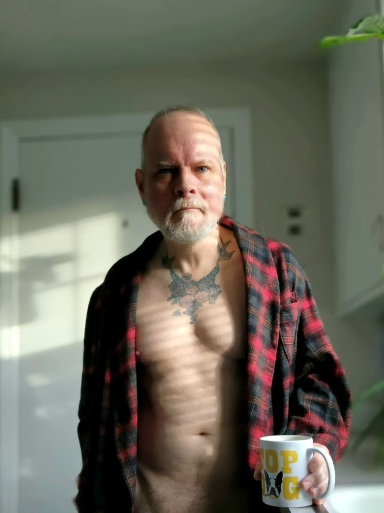Selfie of an older man  in open robe highlighted by sunlight through blinds 