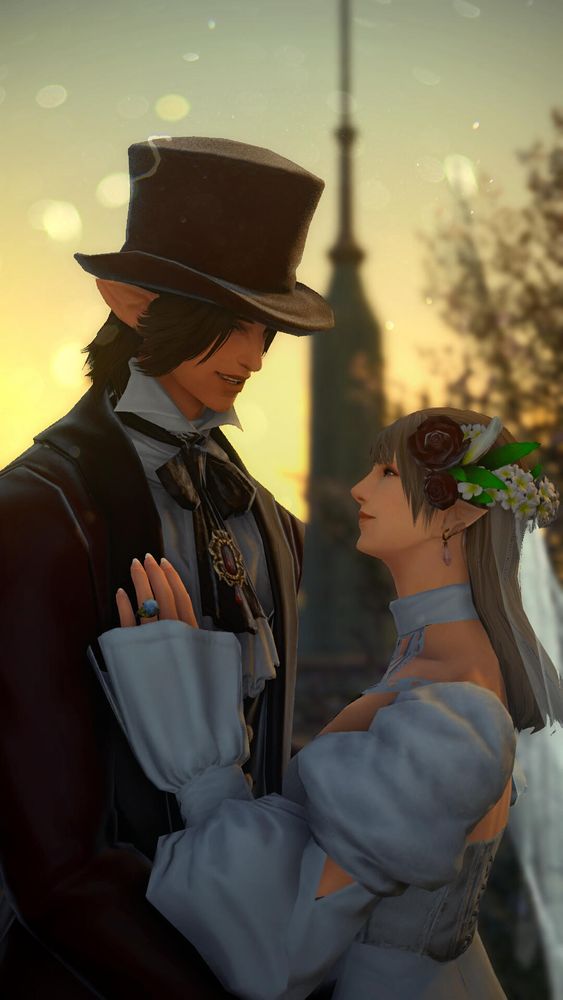 An elezen man and woman look into each other's eyes with a smile as the sun sets over the Pillars on their wedding day. The groom wears a maroon suit with a silk tie and top hat, and the bride wears a white gown, pink earrings and a white veil decorated with maroon roses. 
