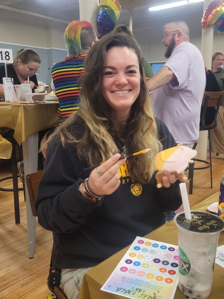 A smiling woman is painting ceramics.
