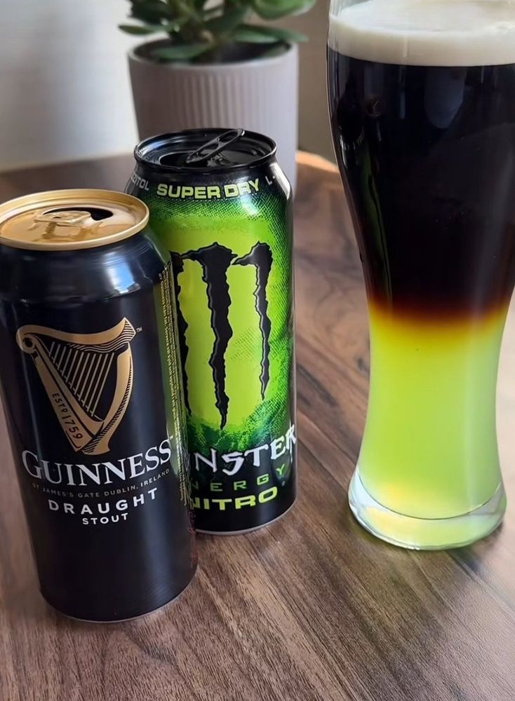 A can of Guinness adjacent to a can of monster energy drink NITRO, both opened. A wheat beer glass stands with a layered pour of Guinness on top and an unholy, radioactive green below. The cursed GONSTER.