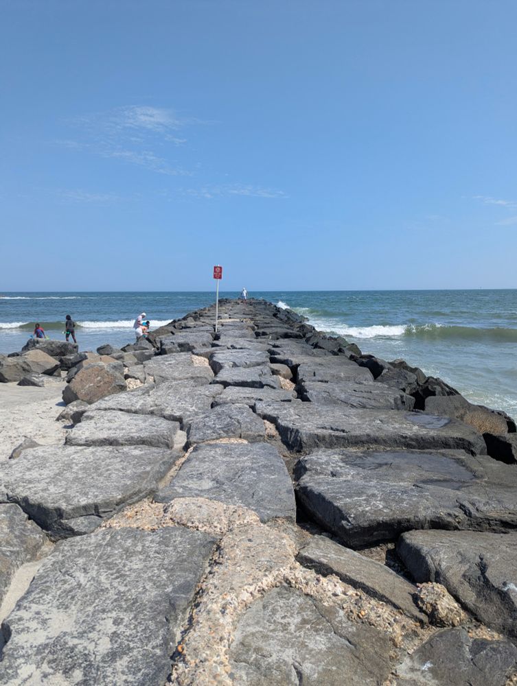 A photo of a rock jetty extending off into the ocean.