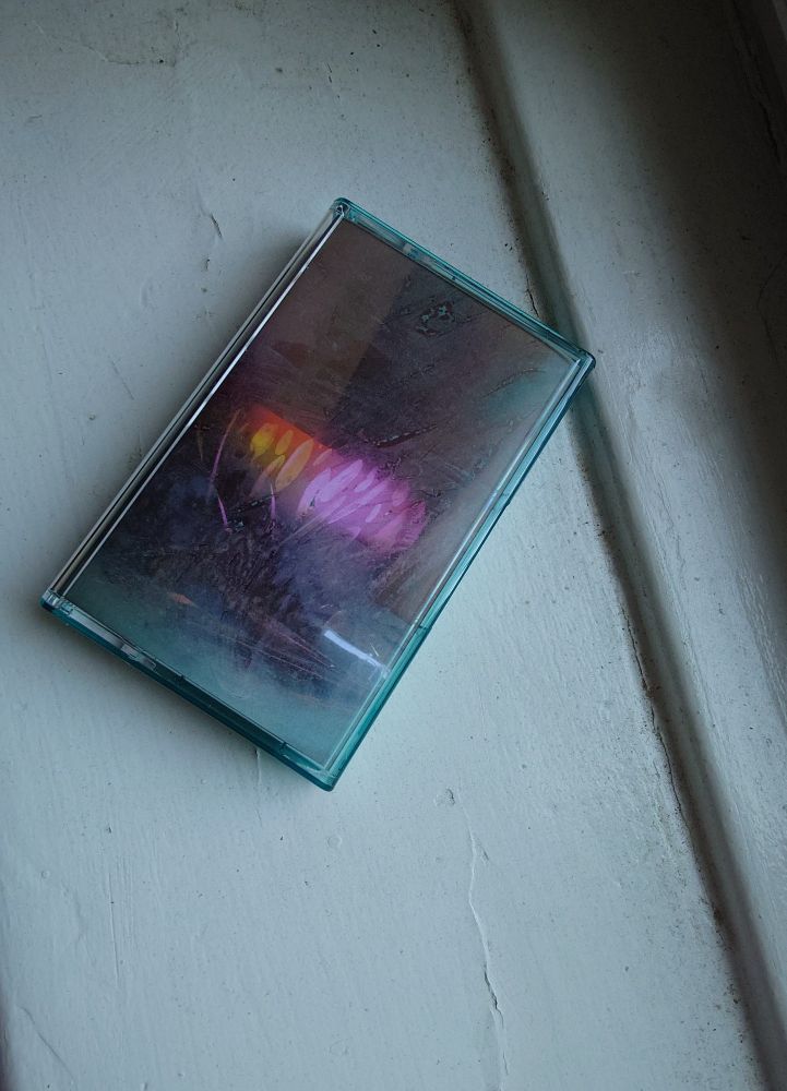 A cassette in a turquoise case with cover art by me taken from my film Can You Hear the Interim (on a  painted window sill in Brooklyn)