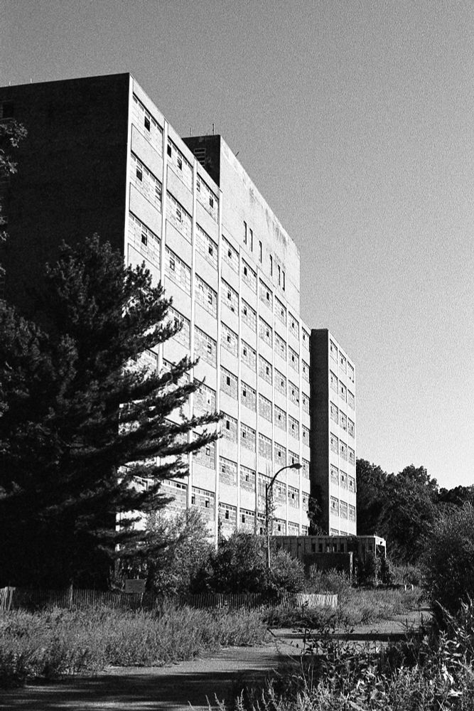 Black and white photo of an abandoned building that looks like a mid-20th-century hospital.

Taken at the abandoned Kings Park Psychiatric Center in Kings Park, NY.

Building 7, a 10 floor medical/surgical building built in 1966. One of the last to close.

https://en.wikipedia.org/wiki/Kings_Park_Psychiatric_Center
