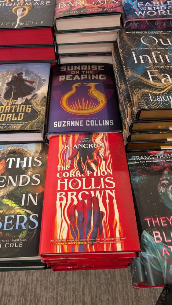 K Ancrum's newest release The Corruption of Hollis Brown on a Barnes and Noble display table beside Suzanne Collins Sunrise at the Reaping (among other YA books as well)