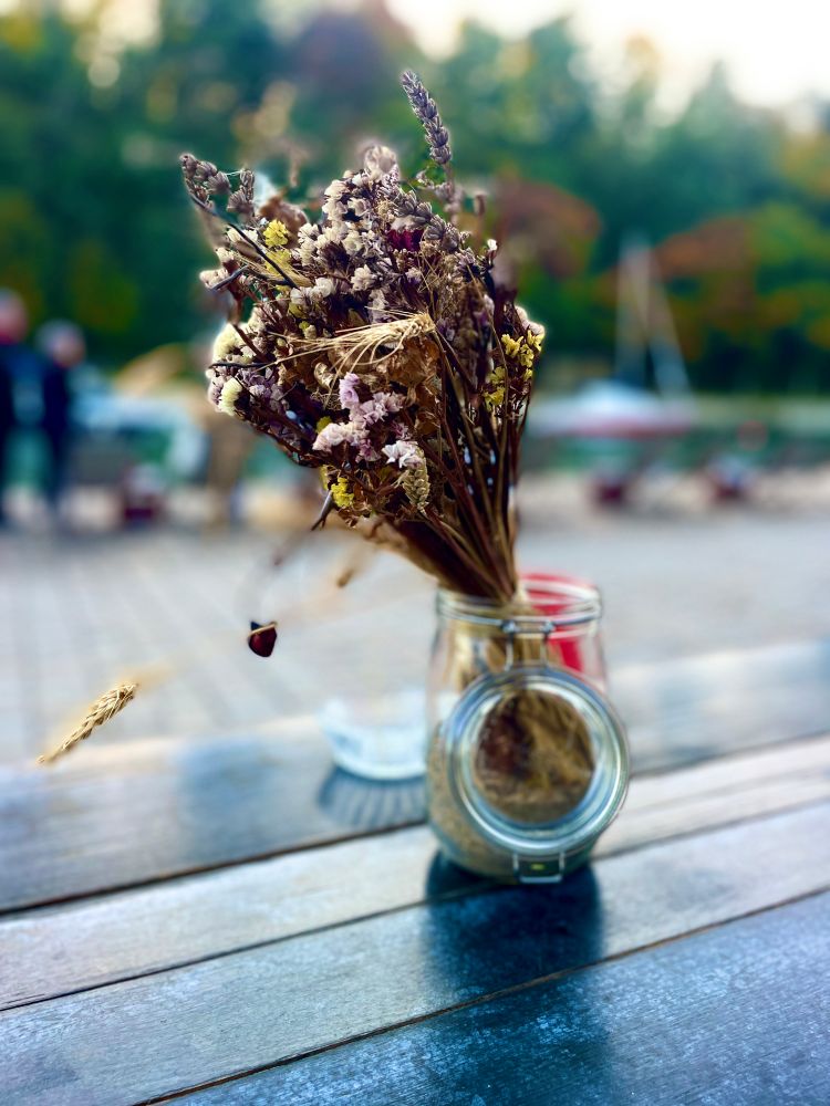 Un bouquet de fleurs séchées dans un bocal sur une table de restaurant 