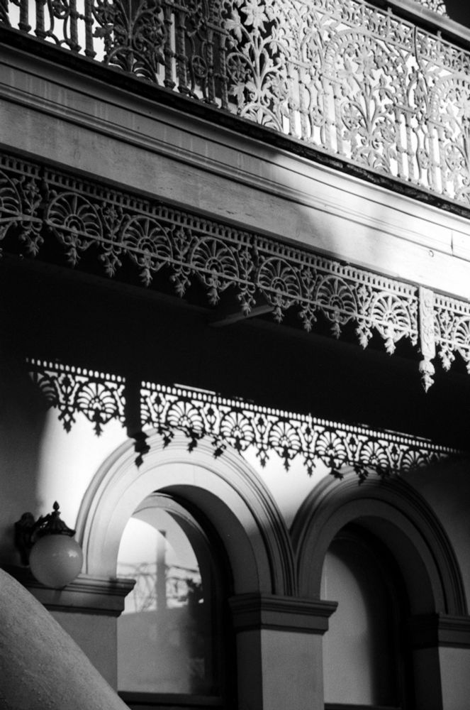 Wrought iron fencing casts hanging from a townhouse cast a shadow on an old Sydney home's arched windows.
