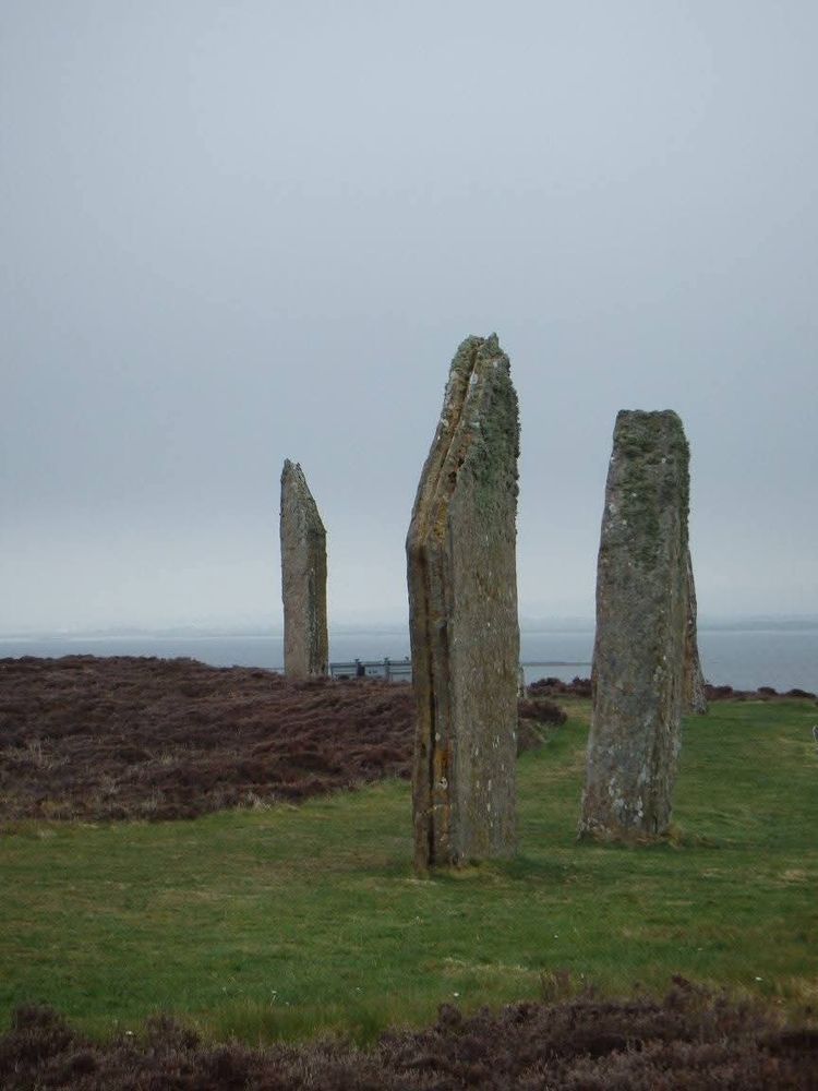 Standing stones in a field with the sea in the background