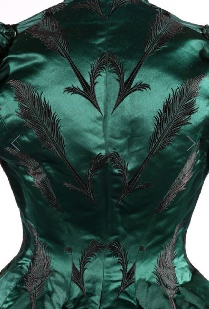 Back view of the bodice of a bottle green satin dress with a pattern of black feathers. This view shows how the pattern matching was executed centre back