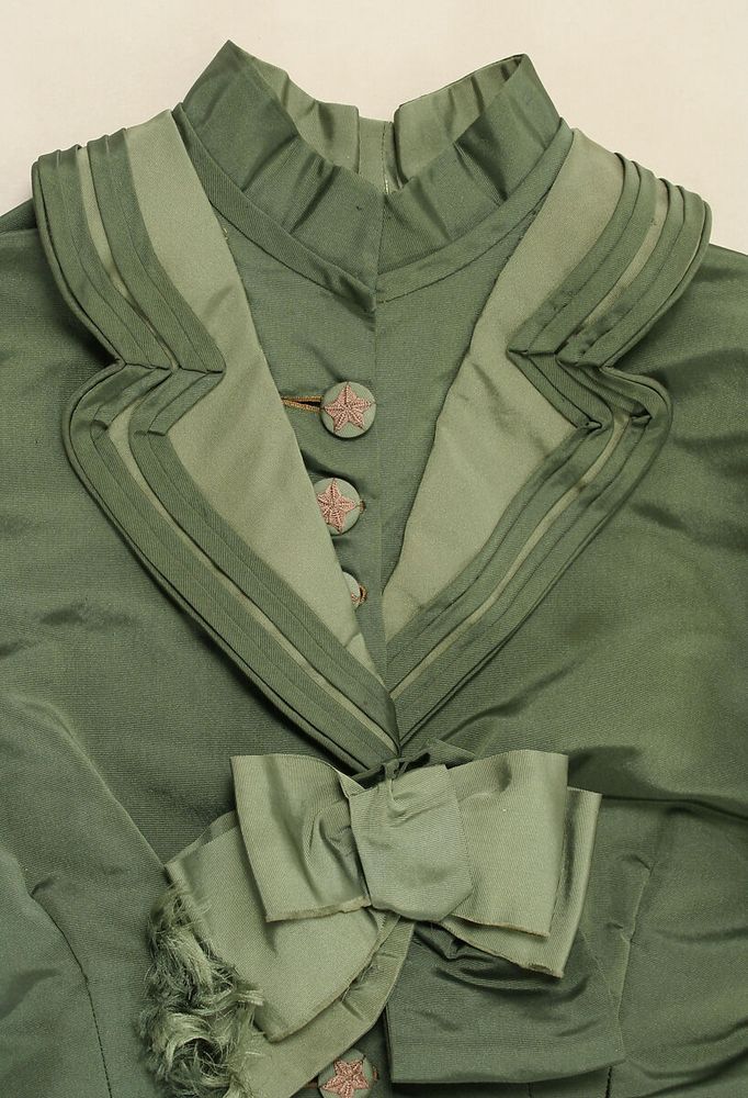 Bodice detail in two shades of green silk with wide lapels, embroidered buttons and a silk bow