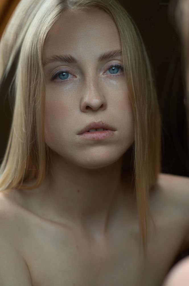 Portrait of a blonde woman reflected in a 200 year old mirror 