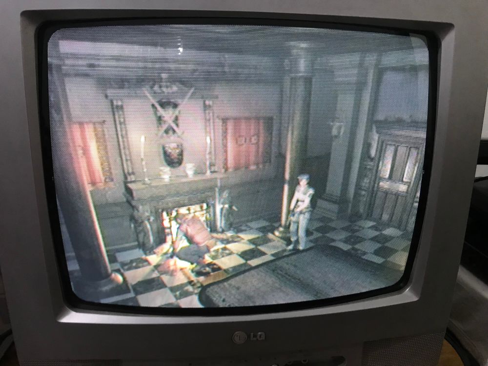 Resident Evil Remake de GameCube na TV tubão. Jill está parada numa sala de jantar, enquanto Barry está agachado examinando uma poça de sangue.