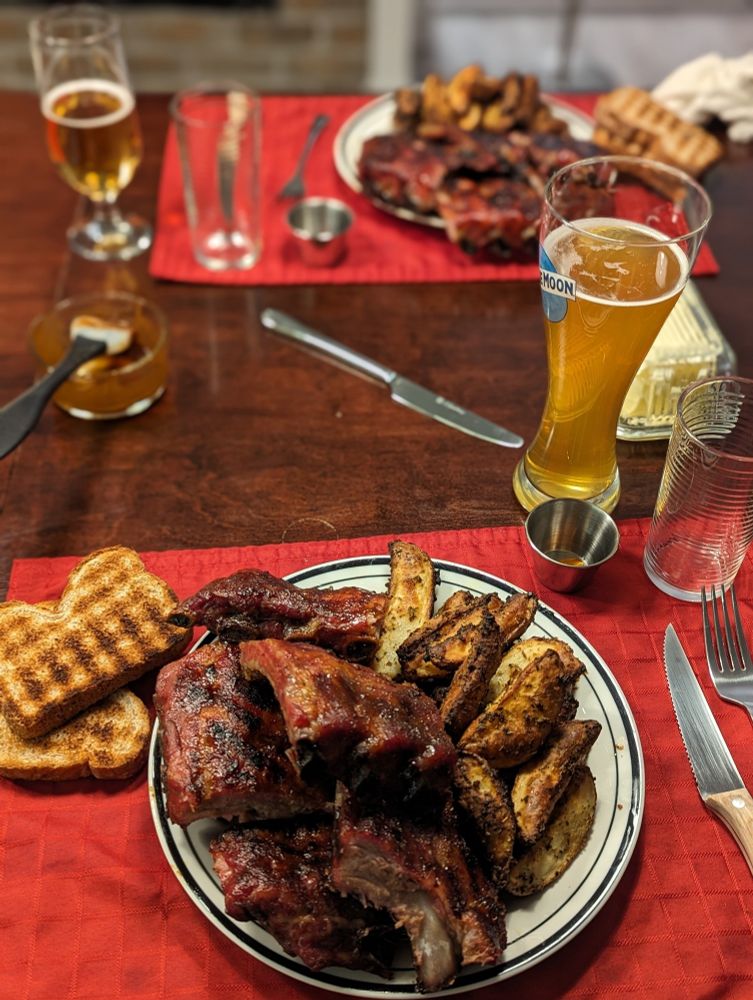 Table d'assiettes de côtes, patates, rôties et bière belge