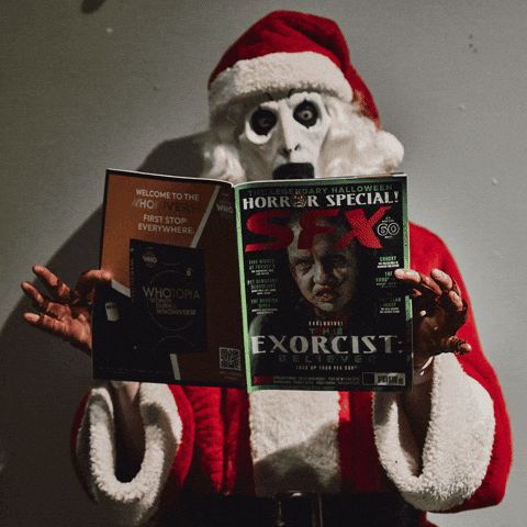 Art the Clown from the Terrifier franchise reading a magazine and laughing in a Santa suit