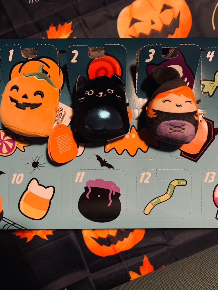 Three Halloween Micromallows for the squishmallow Halloween Advent calendar where the one on the left being a 2 inch pumpkin and the one in the middle being a 2 inch black cat and the one on the right being a 2inch witch.