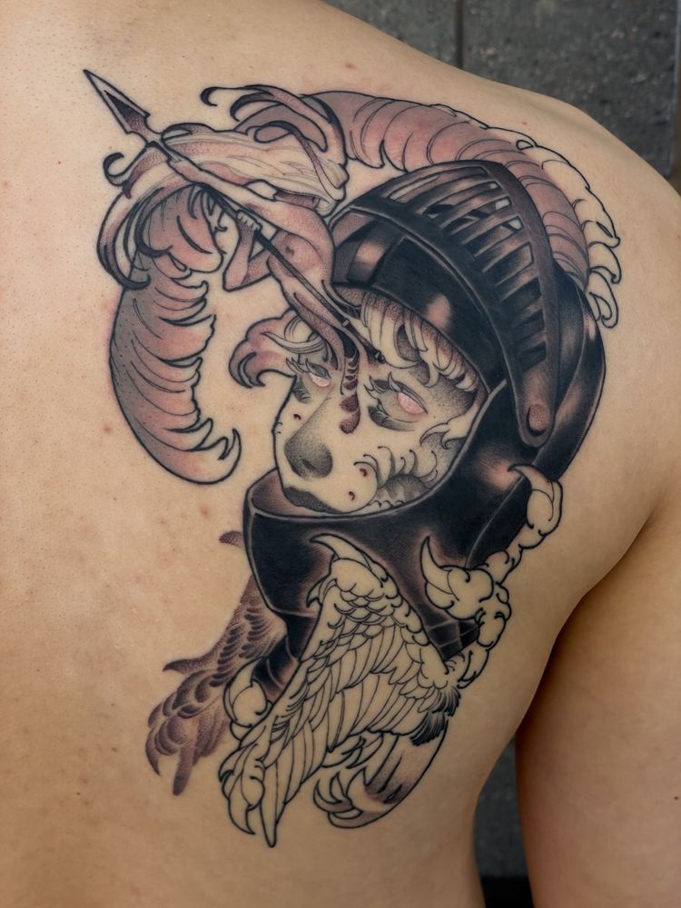 A tattoo depicting a portrait of a knight in a black helmet. A small figure with a spear is emerging from the knight’s forehead.