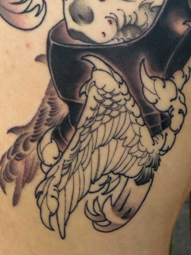A tattoo depicting a portrait of a knight in a black helmet. A small figure with a spear is emerging from the knight’s forehead.