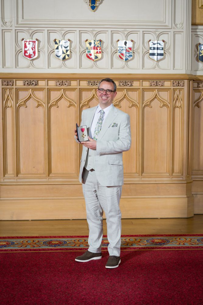 A photograph of Dr Toby Simpson holding his OBE inside Windsor Castle in July 2025