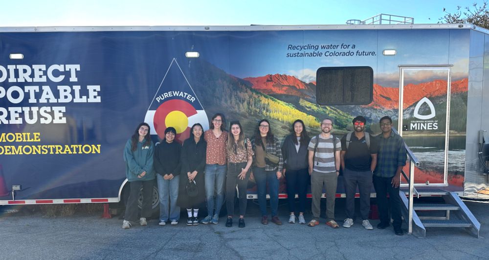 10 WE3 lab students stand in front of shipping container with the words "Direct Potable Reuse Mobile Demonstration" printed on the side alongside images of the Colorado wilderness.