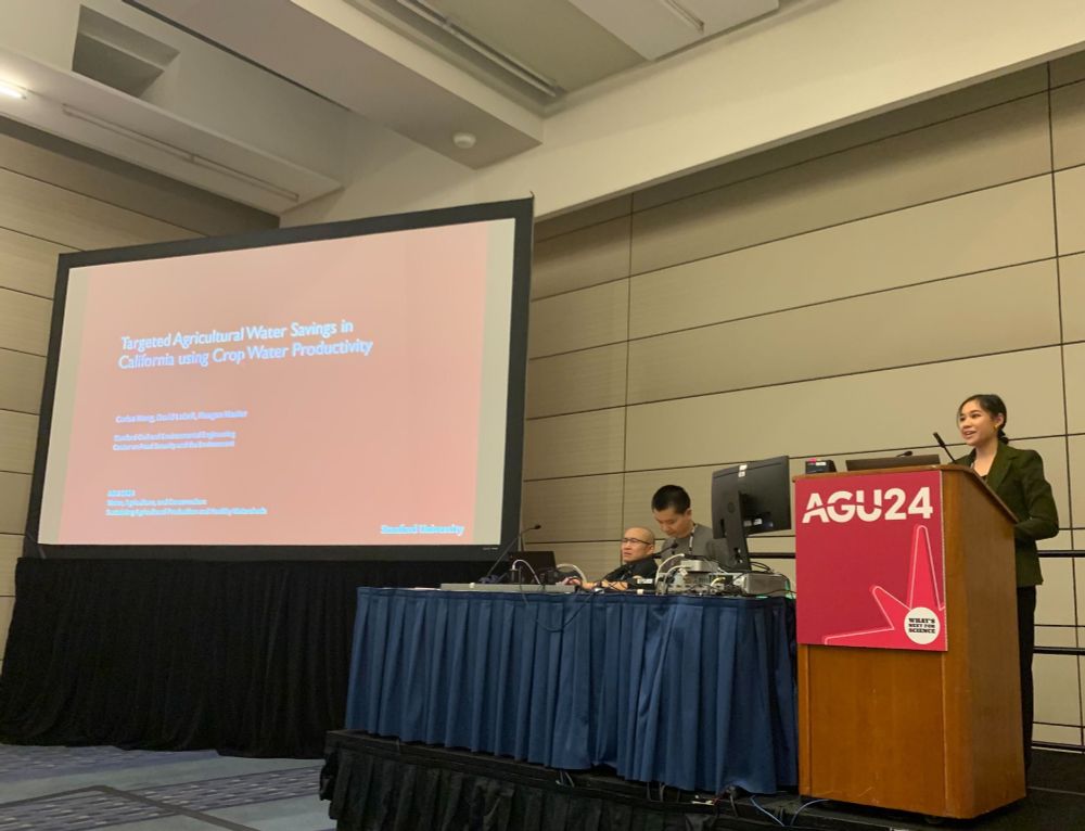 Presenter stands behind AGU podium next to PowerPoint slide