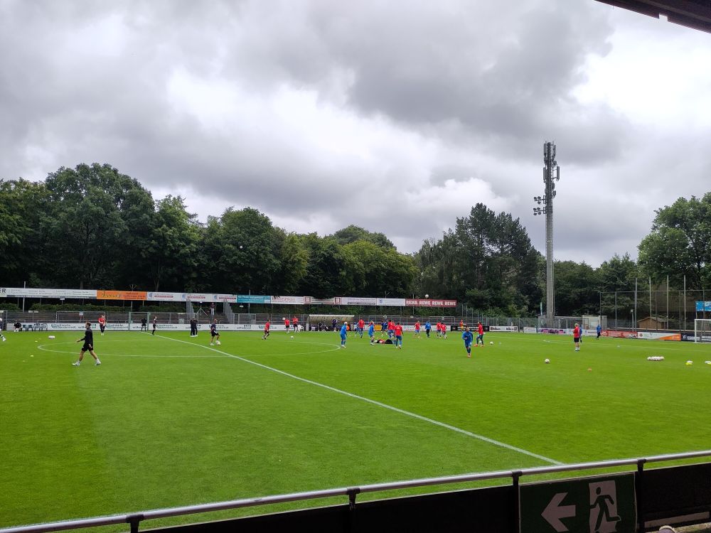 Bild von der Haupttribüne des Edmund-Plambeck-Stadion aus fotografiert. In der rechen Spielhälfte ist dir Mannschaft von Drochtersen/Assel beim Aufwärmen zu sehen. Links die Spieler der U23 des FC St. Pauli. 
