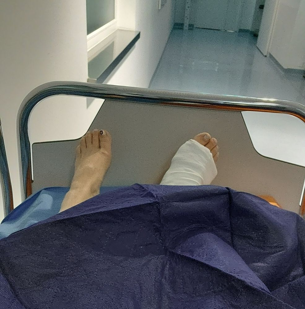 Der Blick auf die eigenen Füße im Krankenhausbett, der rechte ist eingegipst. 
