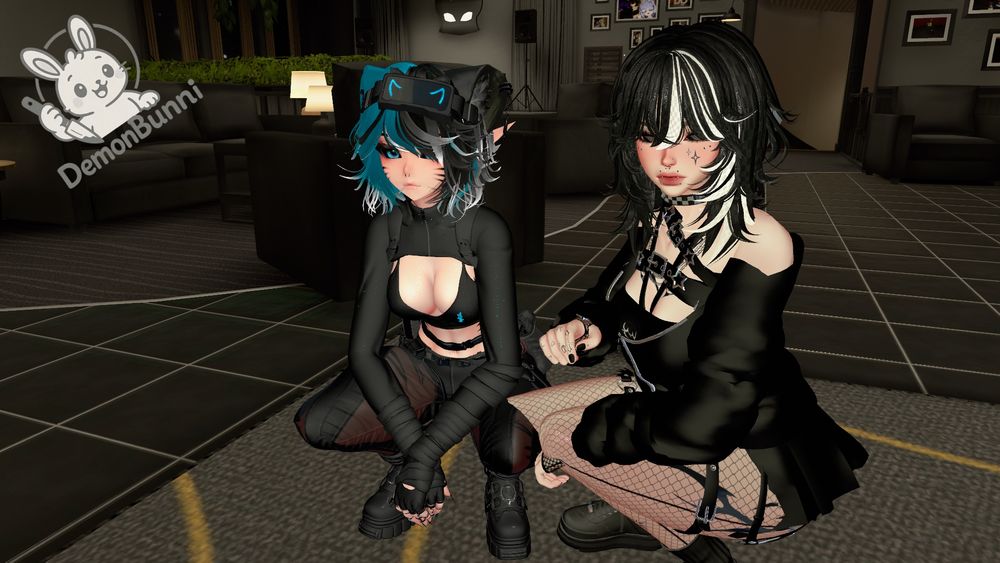 Photograph of two anime-style avatars crouching indoors. The avatar on the left has blue and white hair, blue eyes, and wears a black outfit with a visible midriff. The avatar on the right has black and white hair, wears a black dress, fishnet stockings, and has multiple piercings. A logo with a rabbit and the text "DemonBunni" is in the upper left.