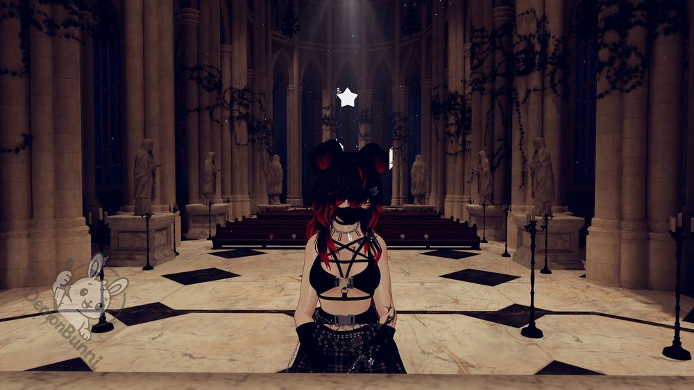 Photograph of a person in a virtual space. The person has red and black hair, a black mask, and is wearing a black outfit with a pentagram harness. They are standing in a large, ornate cathedral-like building with tall columns, statues, and pews. A bright light shines from above. A logo of a rabbit is in the bottom left corner.
