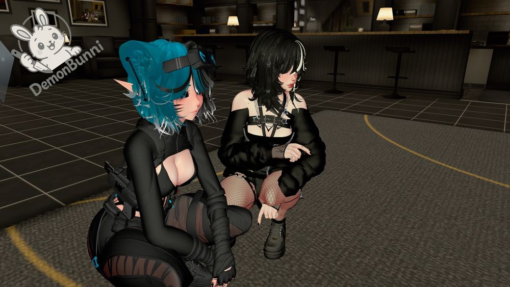 Photograph of two anime-style avatars in a virtual environment. One avatar has blue hair and elf ears, wearing a black outfit with a visible weapon. The other has black hair with a white streak, wearing a black outfit with fishnet stockings. They are crouching indoors, with a bar and stools visible in the background. A logo with a bunny and the text "DemonBunni" is in the upper left.