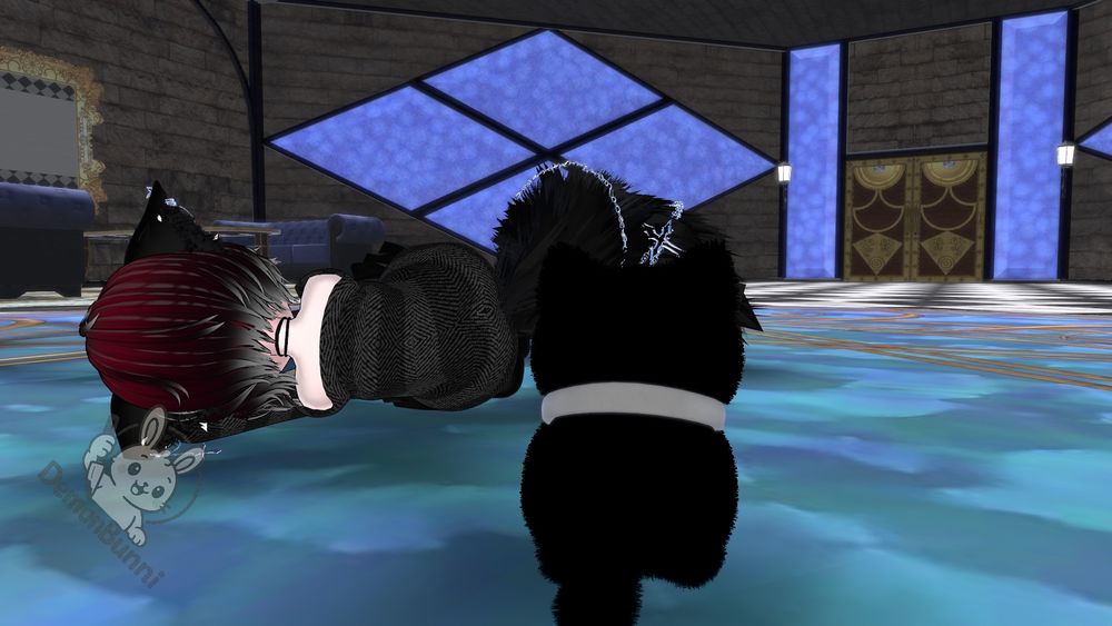 Photograph of two anime characters lying on the floor. One has red and black hair and is wearing a black and gray suit. The other is a black cat with a white collar. The floor is blue and gold, and the walls are gray with blue accents. There is a logo in the bottom left corner that says "DemonBunni".