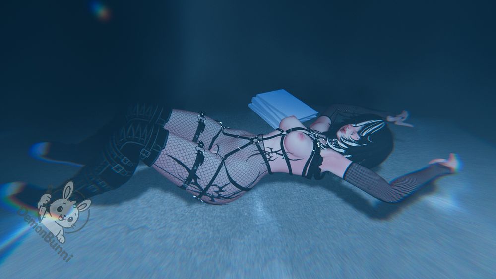 Photograph of a woman lying on her back, wearing fishnet stockings and a black harness, with a stack of papers next to her. A "demonBunni" logo is in the lower left corner.