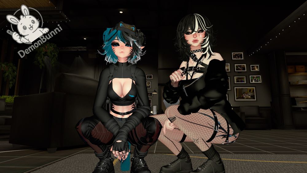 Photograph of two anime-style avatars crouching in a dark room. The avatar on the left has blue and white hair, cat ears, and is wearing a black crop top and pants with red accents. The avatar on the right has black and white hair, and is wearing a black top, fishnet stockings, and a harness. The logo "DemonBunni" is in the upper left corner.