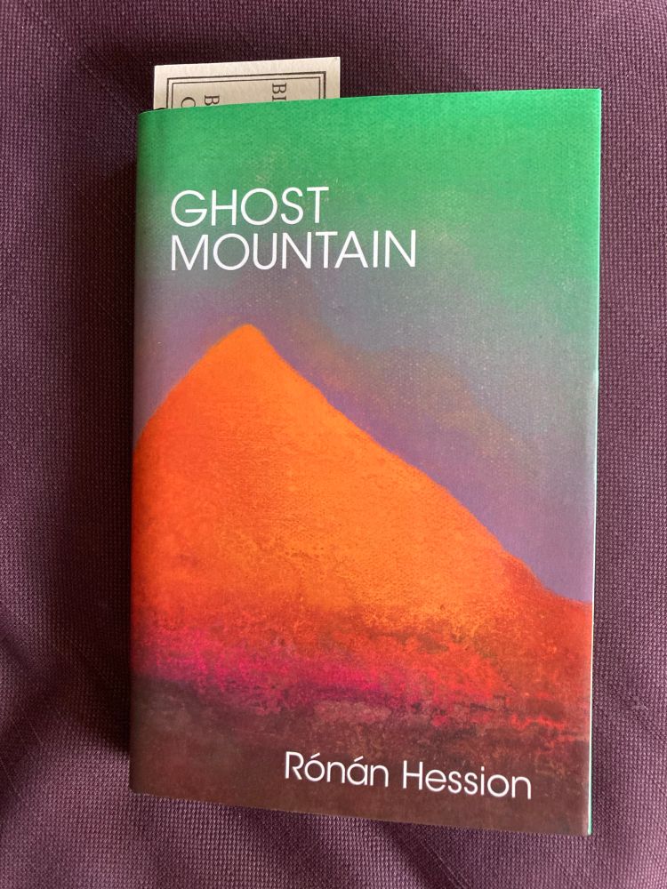 Book cover of Ghost Mountain by Ronan Hession. Orange mountain with a green sky fading to pink at the horizon. 