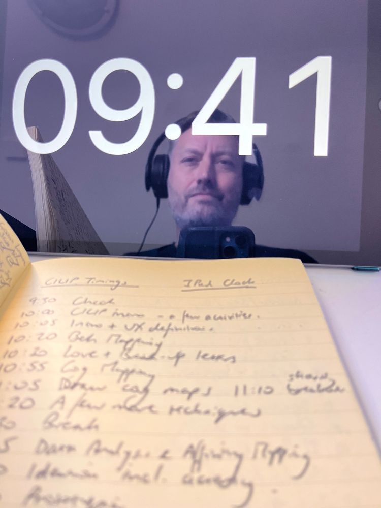 Full screen clock on iPad with reflection of me, and notebook with handwritten course schedule 