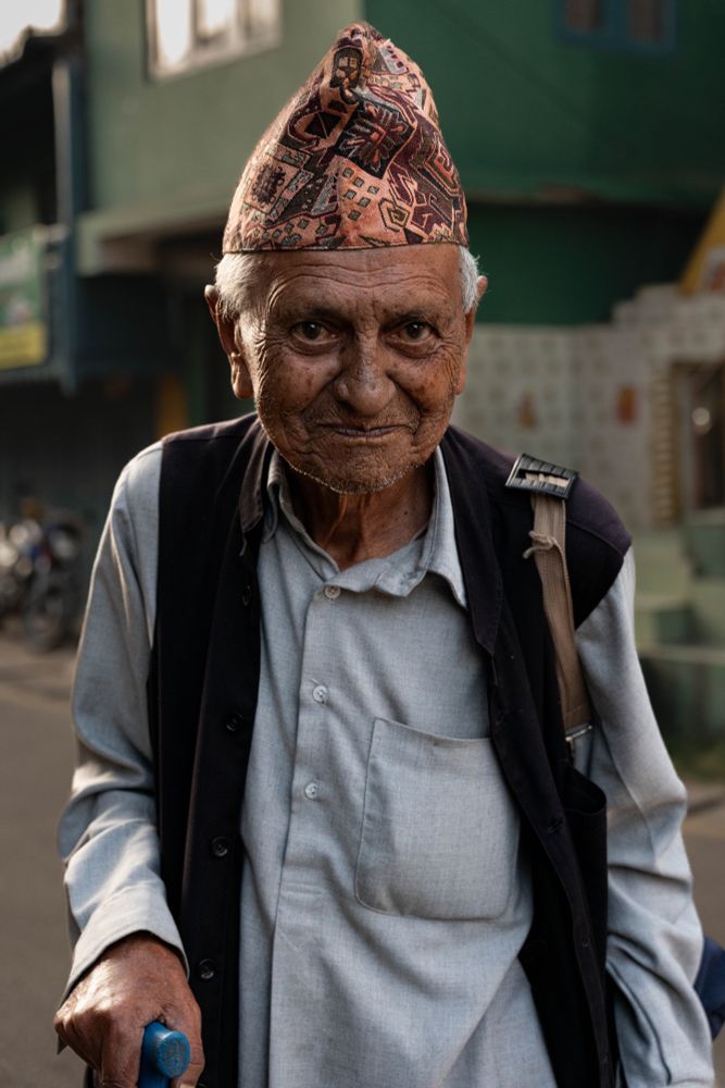 An older gentleman wearing a vest and topi in the Ilam bazaar. 
