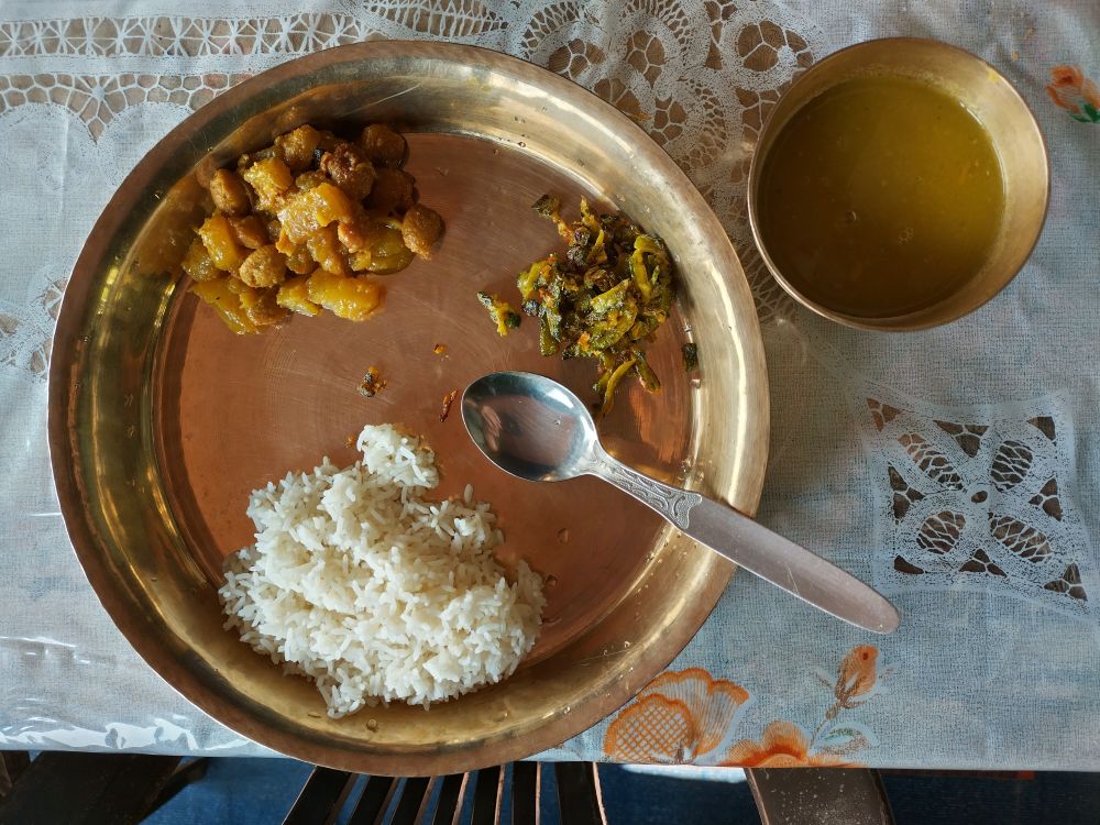 Dal Bhat. Rice, pumpkin with soybeans, local greens and dal soup on a traditional brass plate.