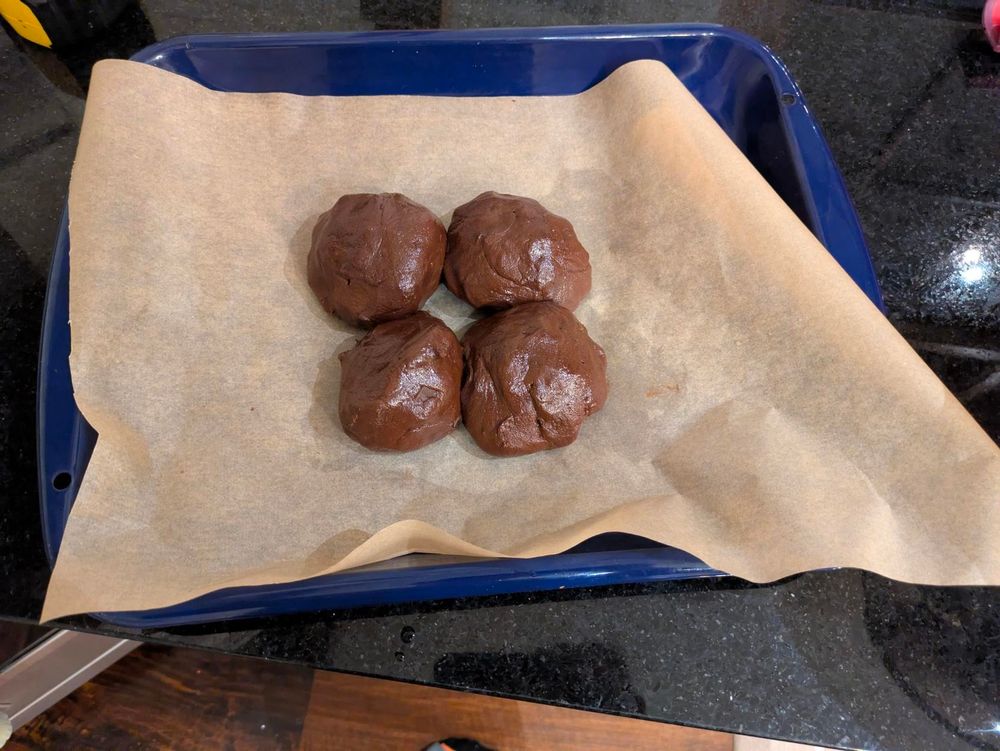 4 gigantic balls of batter about the size of my hand, laid out on a baking sheet