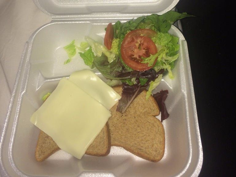 Two pieces of cheese, lettuce, and tomato on wheat bread, photo from fyre festival