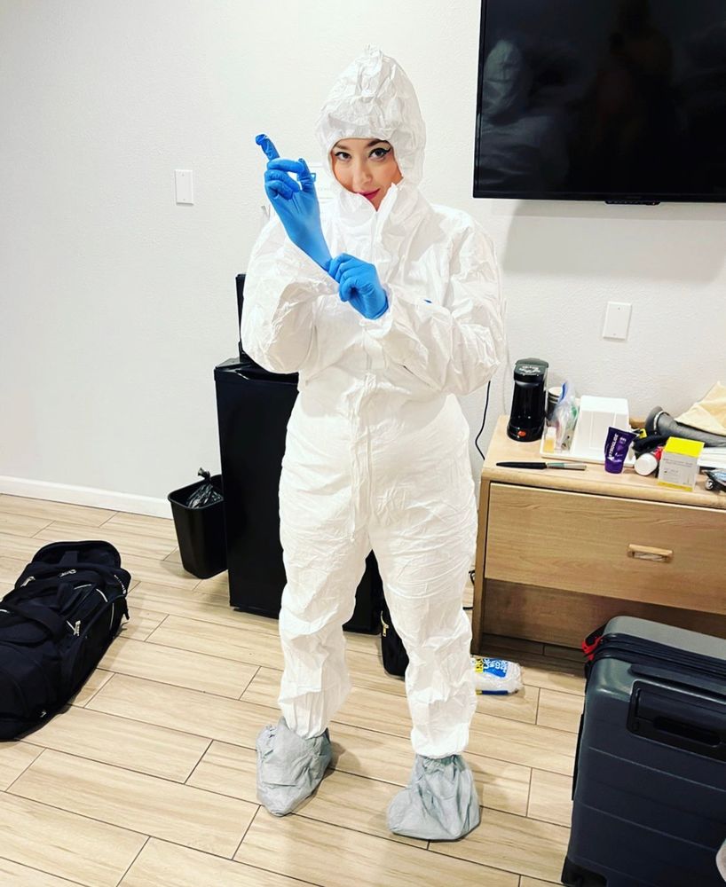 violet in standing in a hotel room wearing head to toe medical ppe