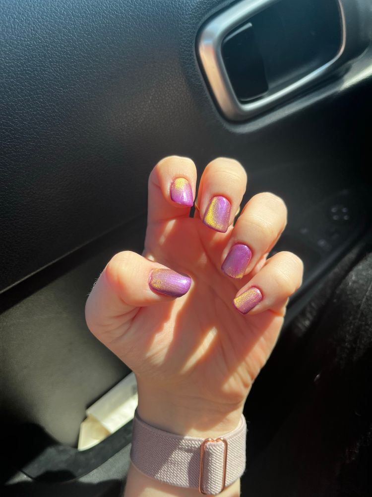 a purple gel polish applied to someone’s nails on their left hand; the nails have a yellow magnetized effect 