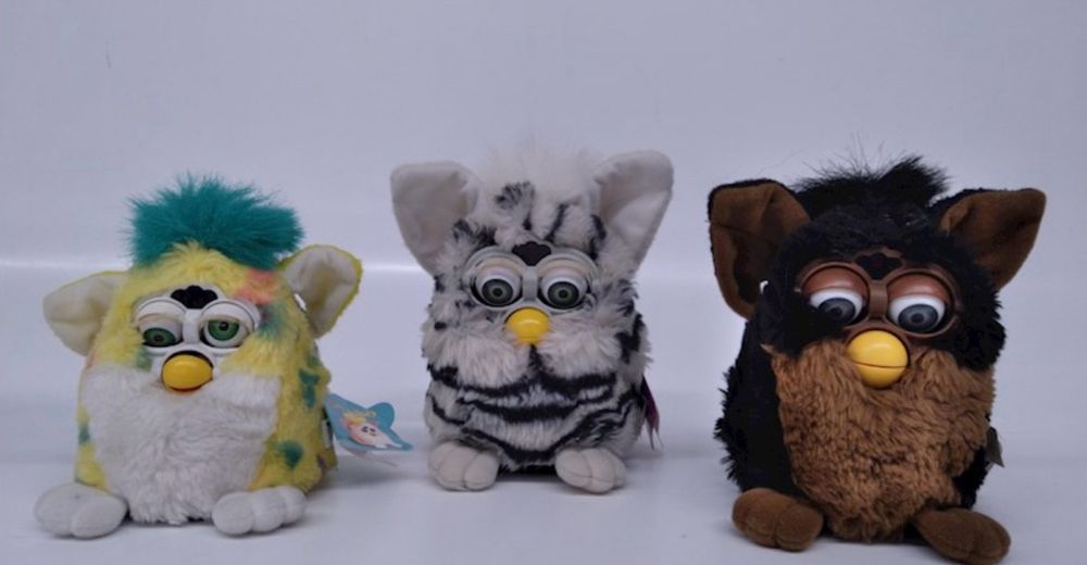 3 Furbies in a row one has wonky eyes the other two are looking down