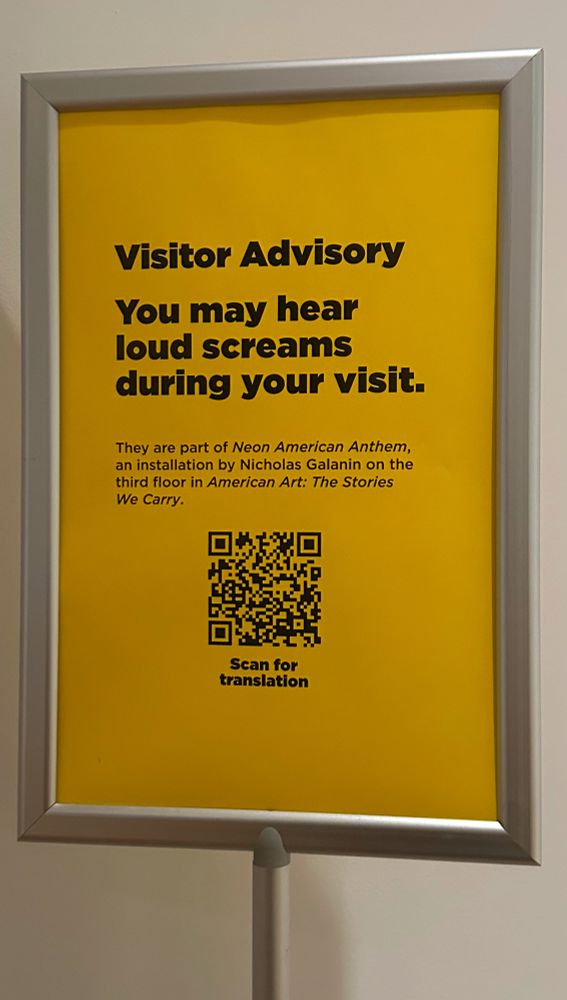 A sign that says

Visitor Advisory
You may hear loud screams during your visit.
They are part of Neon American Anthem, an installation by Nicholas Galanin on the third floor in American Art: The Stories We Carry.
Scan for translation