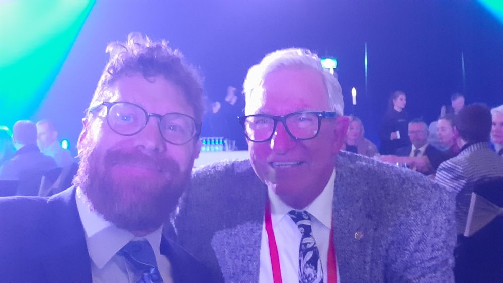 Two men in suits side by side at an event. A younger one (the author) who is very proud to be sitting next to an older white haired man who along with his family was in the film "The Dish" about the radio telescope in Parkes NSW 