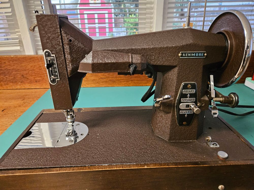 A vintage portable sewing machine in a chocolate brown cast iron looking body.  The sharp lines and angles give it an Art Deco vibe.