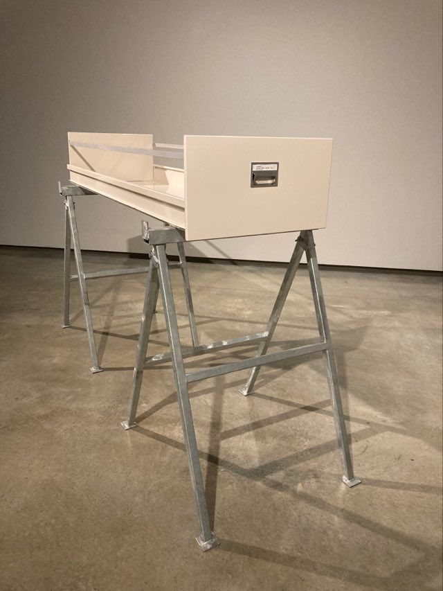 Photo shows a metal drawer from a filing cabinet (of extended length) standing on top of trestle legs