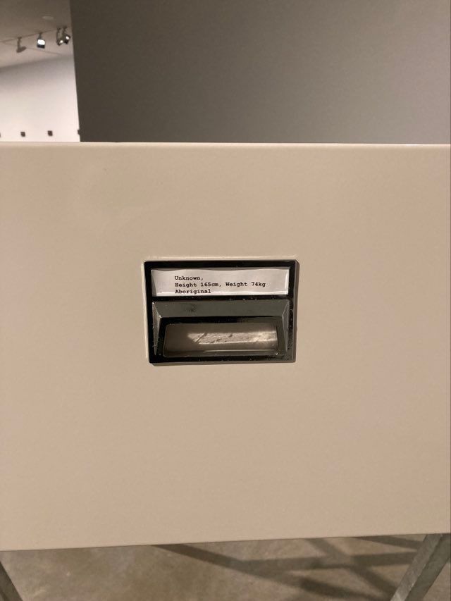 Photo shows the front side of a filing cabinet drawer labelled with typewritten words:
'Unknown.
Height 165cm, Weight 74kg
Aboriginal"