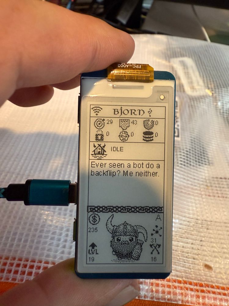 Raspberry Pi Zero 2 W with an e EPaper HAT display.
The display has (from left to right, top to bottom, row by row):
A full WiFi icon, the word Bjorn, and a usb symbol.
A target icon with “29” next to it representing hosts, a Ethernet jack icon with the number “43” representing found open ports, a broken shield icon with a “0” representing vulnerabilities detected.
A unlocked lock icon with the number “0” representing cracked credentials, a face of a zombie with the number “0” next to it representing zombified machines, and a stack of disk platters (like a database icon) with the number “0” next to it representing stolen files.
A house with horns and the text “IDLE”.
A message stating “Ever seen a bot do a backflip? Me neither.”
A coin with the number ”235”, the text “LVL” with the number “19”, crossed axes with the number “16”, and a network icon with the number “21”, and in the center of all of it is a cartoon Viking with a big beard and beady eyes, with a helmet with the left horn pointing up and the right pointing down, holding a bottle.