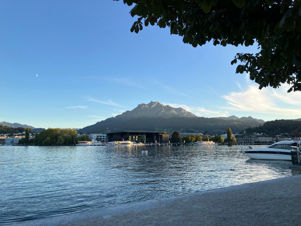 At the edge of a lake with one large mountain seen not far away from the city on the other side 